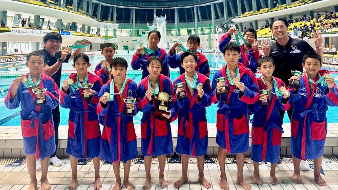 写真：大会会場で表彰式後に撮影した集合写真。選手たちはトロフィーと金メダルを持ち、うれしそうな表情を浮かべています