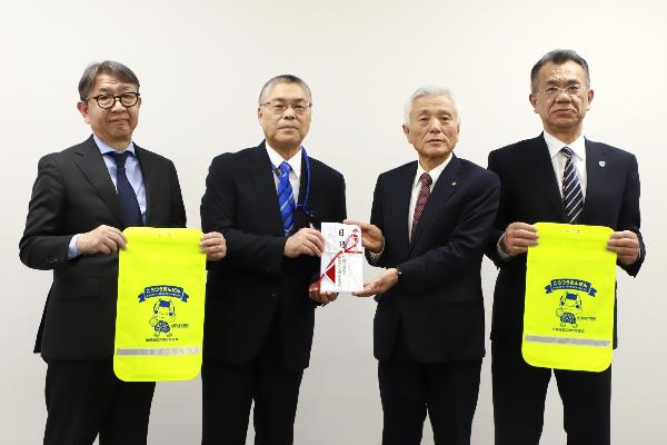 写真：今井会長が近藤教育長に目録を贈呈し、石坂副会長と魚野副会長がランドセルカバーを持っています。