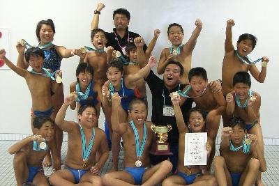 写真：優勝した小学生チームの写真です。首に金メダルをかけて喜んでいます