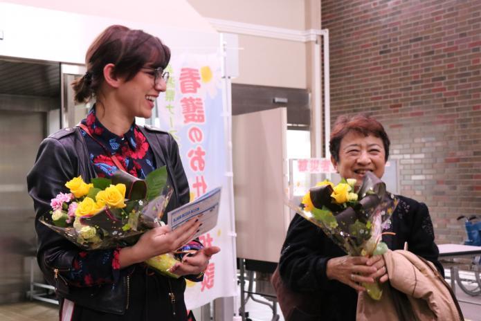 歓迎の花束を受け取り、笑顔のイェレナ・イェレミッチさんと角崎さんの写真