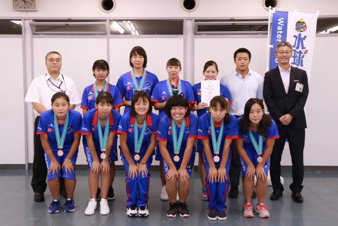 栗山選手と銅メダルを付けているブルボンウォーターKZ高校生女子チームと教育長と市長の集合写真
