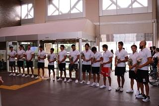 水球男子日本代表の選手が横に一列に並び、職員からの歓迎を受けている様子の写真