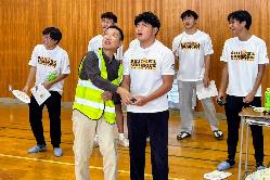 写真：産附の先生からレクチャーを受けながらマレーシアの選手がドローンを操作する様子