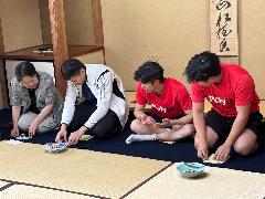 写真：茶道の先生が選手に主菓子の取り方を教えています