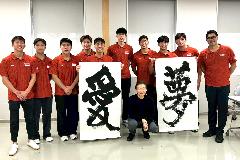 写真：指導していただいた今井先生を囲んで記念撮影。愛、夢と書かれた作品も写っています