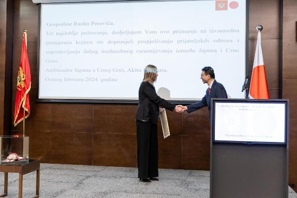 写真：今村大使から表彰状を受け取った後に握手をするスネジャナ・ペロビッチさん