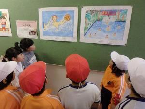写真：掲示板に貼ってある2つの水球の絵を見る中通小学校の児童たち