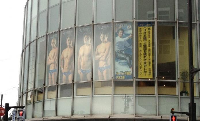 市民プラザの窓に水球4選手と富澤選手のタペストリーが掲示してある写真