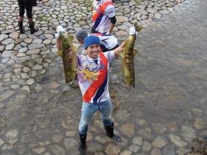 写真：フィリピンの選手が両手に鮭を持って満面の笑みを浮かべています
