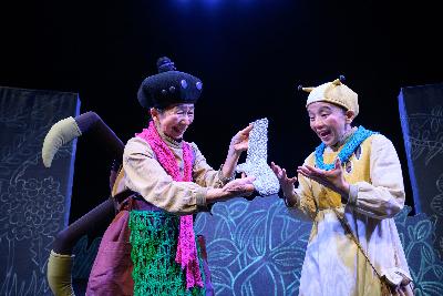 写真：舞台劇「クモばんばとぎんのくつした」のワンシーン。ぎんいろをしたくつ下を持つクモばんばと、それを目を輝かせながらみつめるニュッル