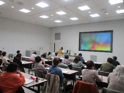 写真：スライドに表示される資料を見ながら講師の話を聞く参加者