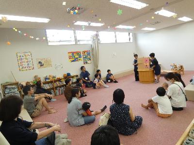 写真：たくさんのお客さんの前で2人の子どもが大型絵本を読み聞かせています