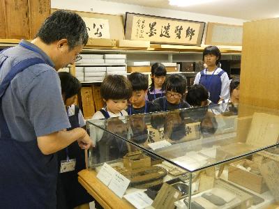 写真：図書館3階の中村文庫の見学の様子。ガラスケースに入った寄贈資料を興味深そうにのぞき込む子どもたち