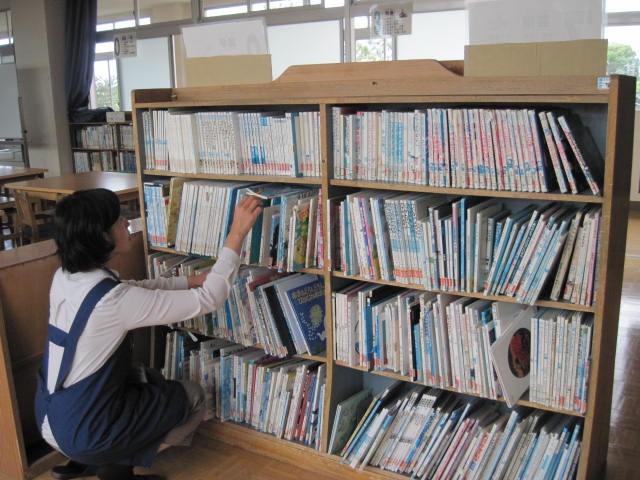 学校読書支援員が本棚の本を整えている写真