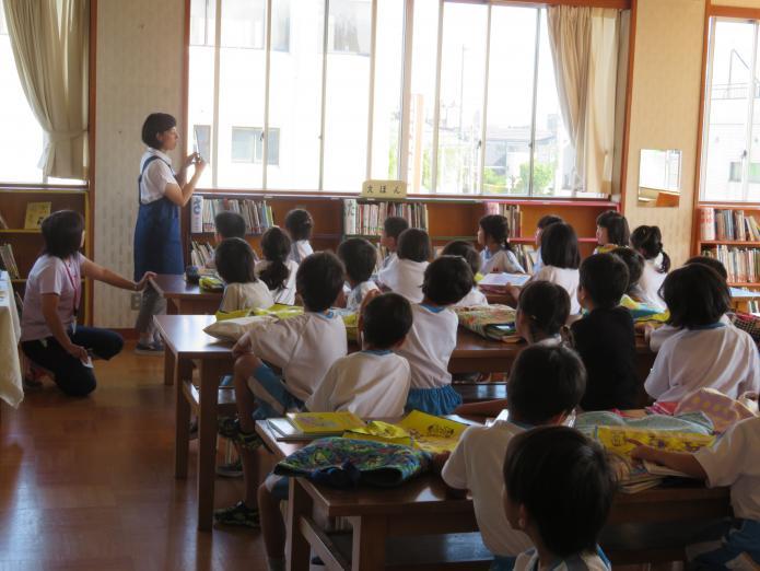 学校読書支援員が児童に図書室の使い方を説明している写真