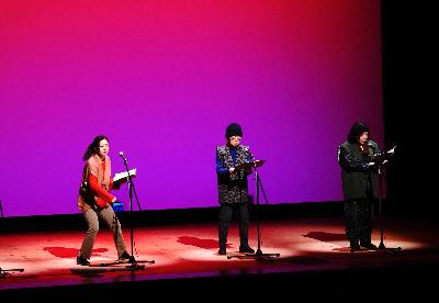写真：たろうの会による朗読会の様子。ステージで朗読する3人のメンバー