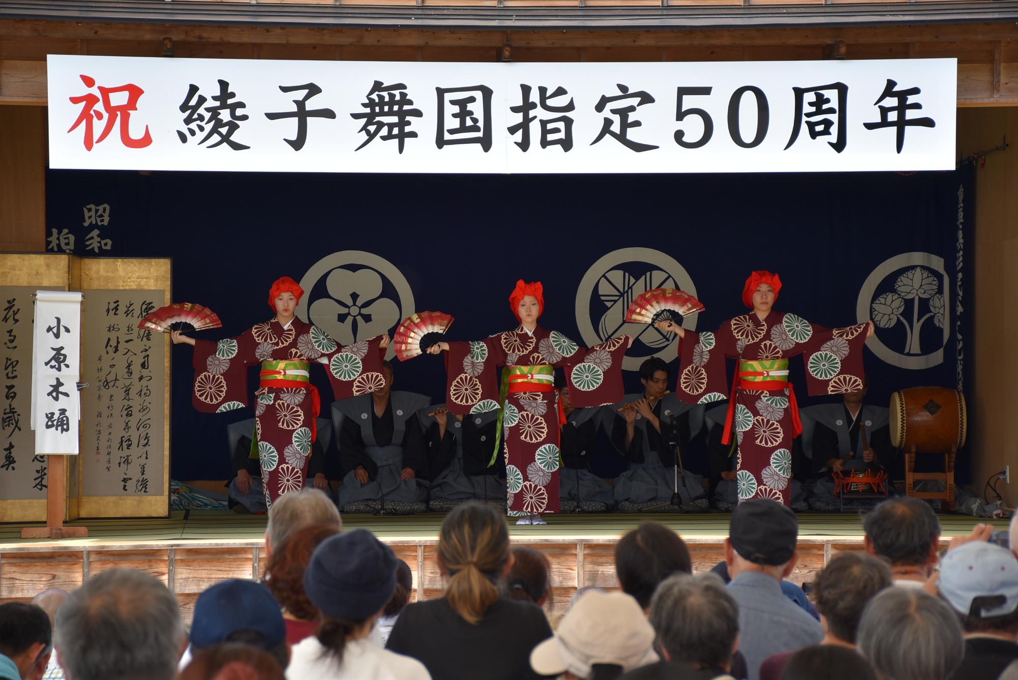 三人の女性が、右手に開いた扇を、左手は着物の袖をつまみ、両手を広げ踊っている写真