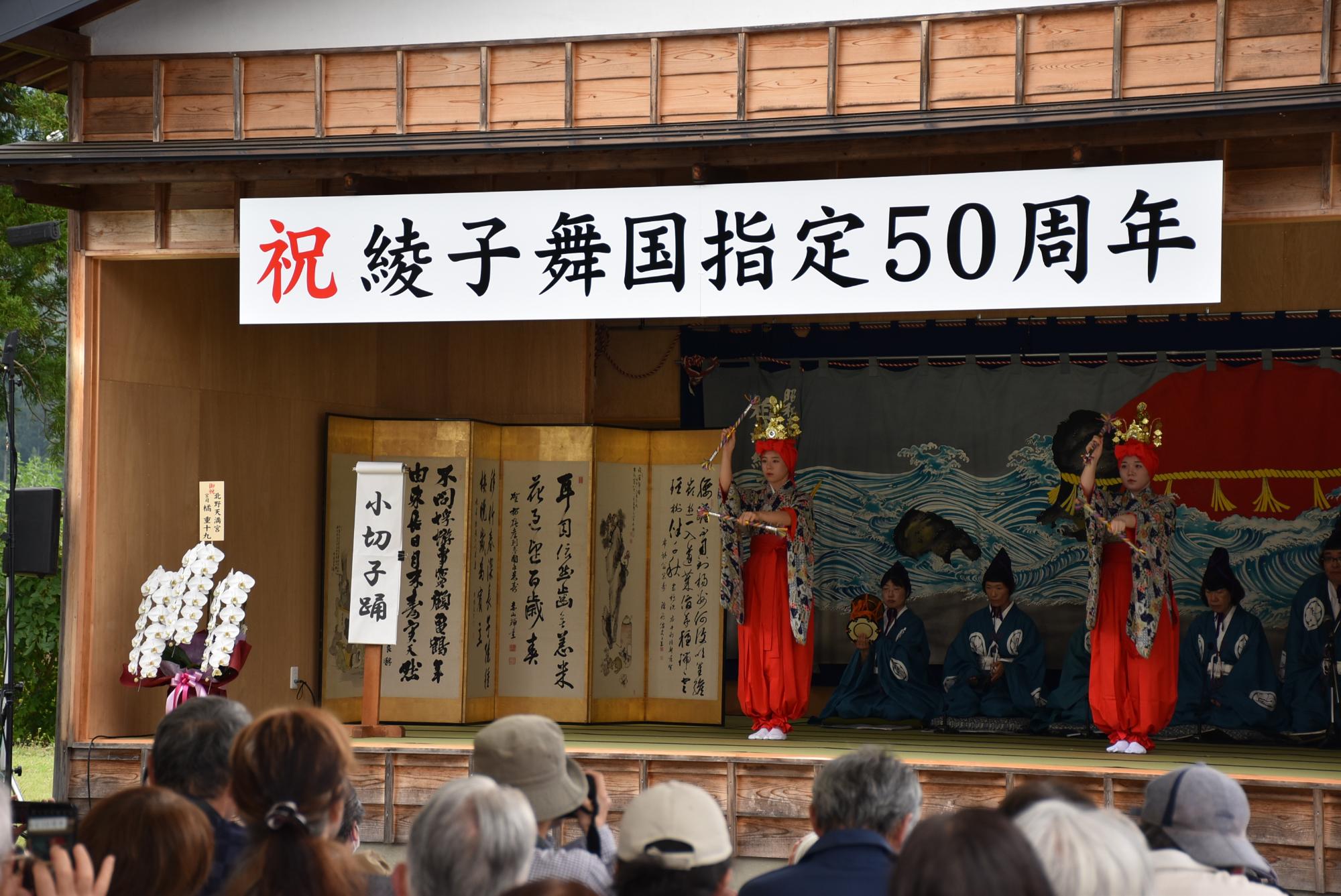 二人の女性が頭に赤い「ゆらい」と「てんがん」を被り、両手に持った綾竹を打ち鳴らしながら踊っている写真