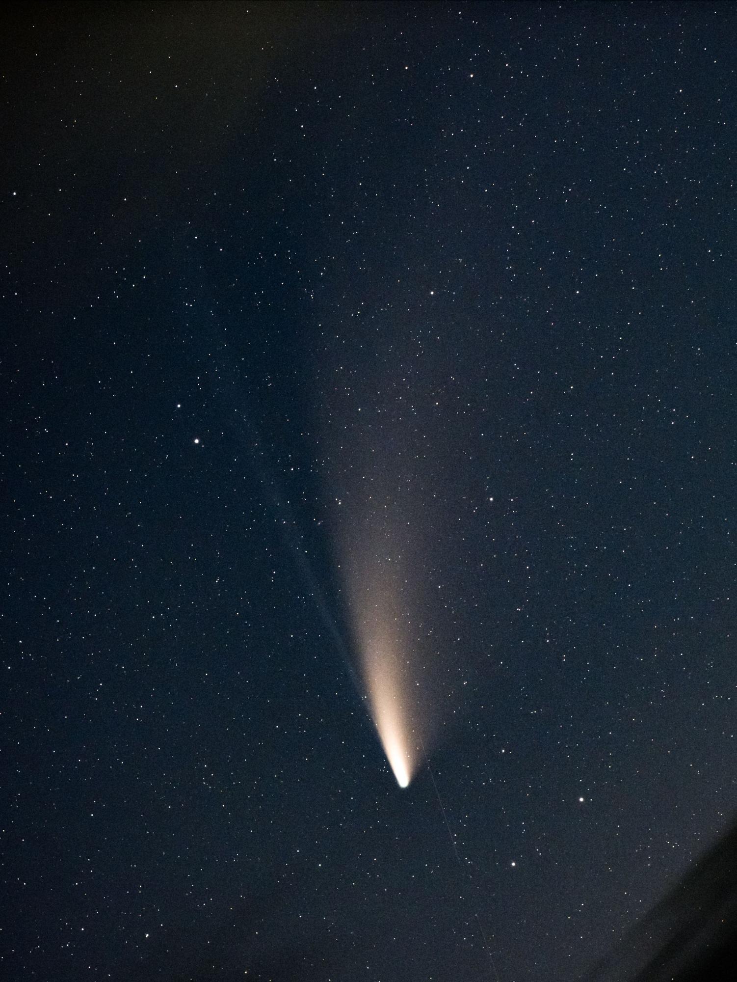 写真：夜空に流れるネオワイズ彗星。写真の上方にかけて、彗星の尾が長く伸びています