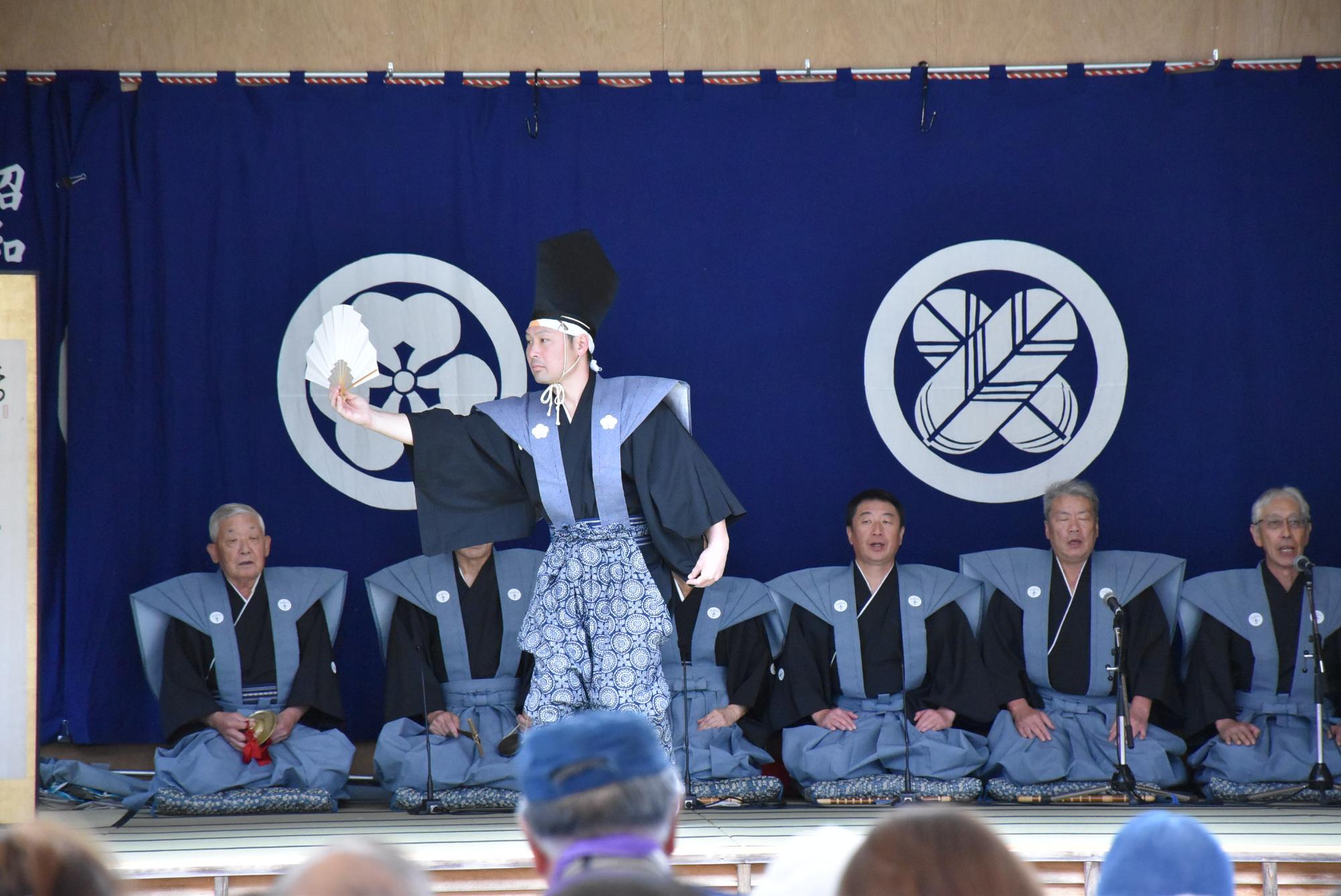 一人の男性が右手に扇を持ち、横に腕を伸ばして舞っている写真