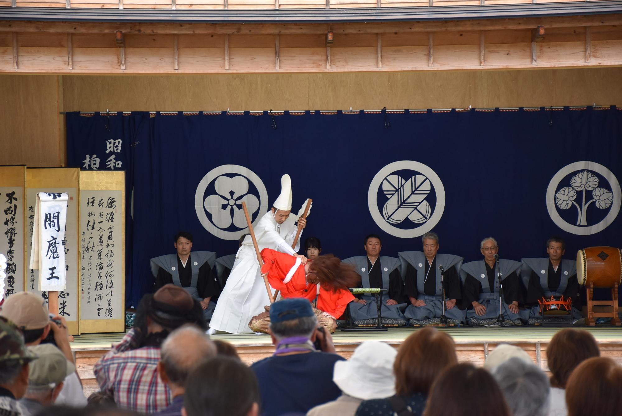 赤い着物に顔が隠れるほどの長髪の閻魔王と全身真っ白な衣装を着た天下無双の朝比奈の狂言。朝比奈が閻魔王の襟をつかんで揺さぶっている場面の写真