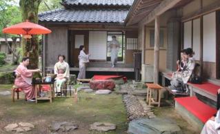 和服姿の女性たちが、飯塚邸の縁側や庭でお茶を楽しんでいる写真