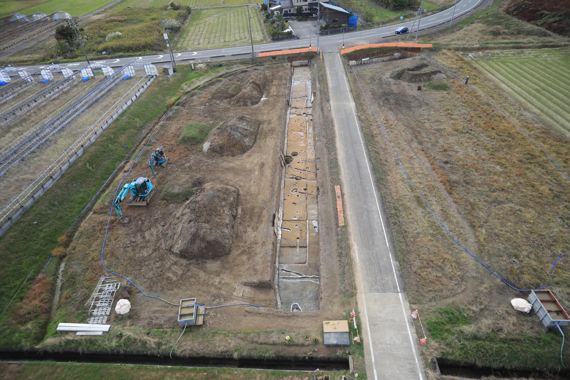 写真：遺跡を空中から撮影したもの。道路に沿うように発掘された遺跡が見えます。