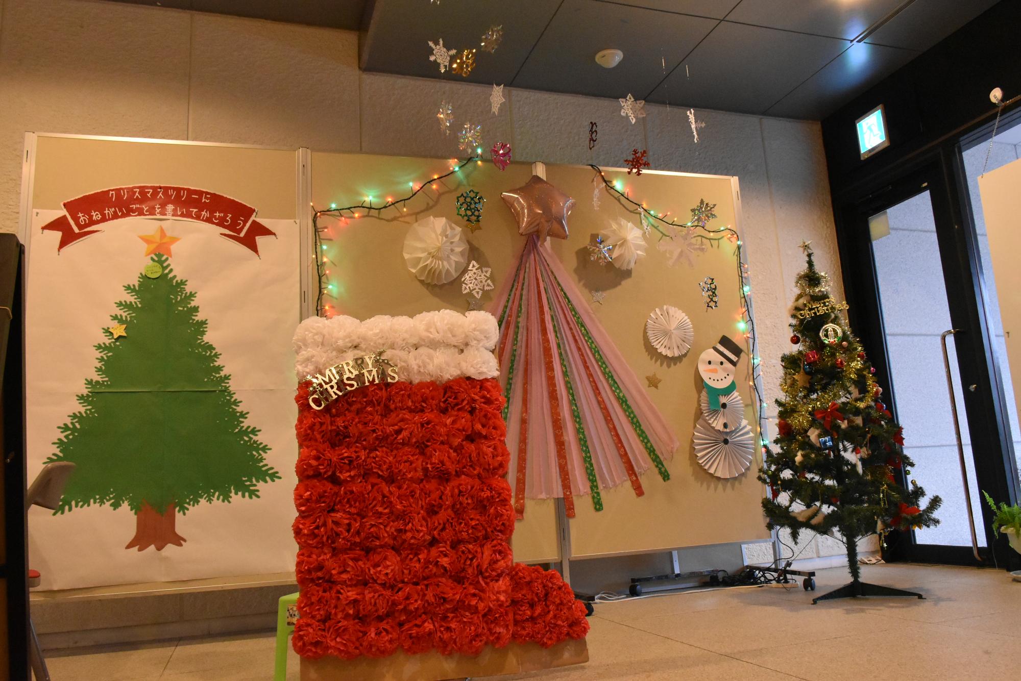 クリスマスフォトコーナーの全体写真。手前に大型クリスマスブーツ、壁面にツリーやクリスマスらしい飾り付けがしてあります。