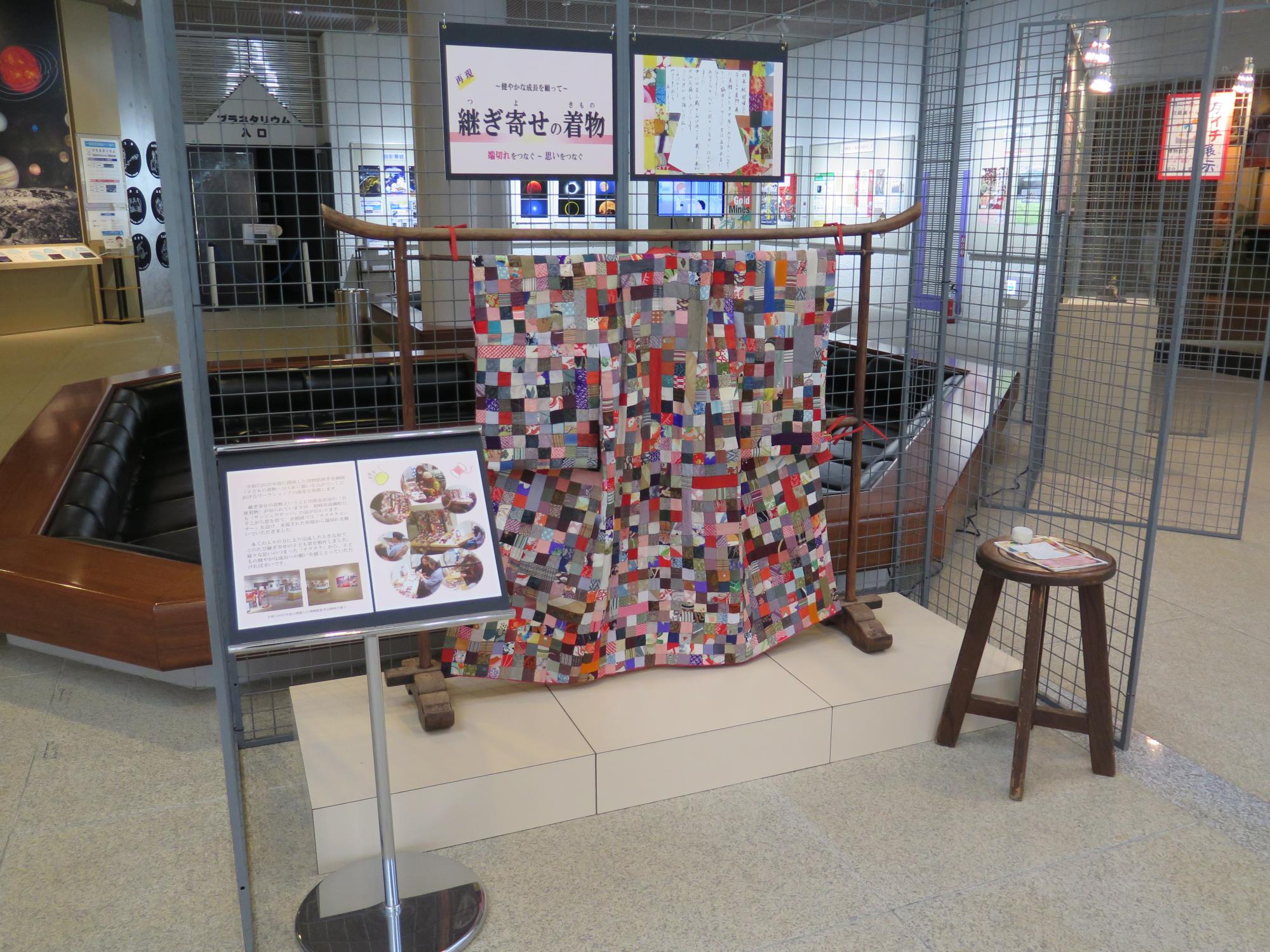 写真：衣紋かけに、継ぎ寄せでできた子どもの着物が展示されています。