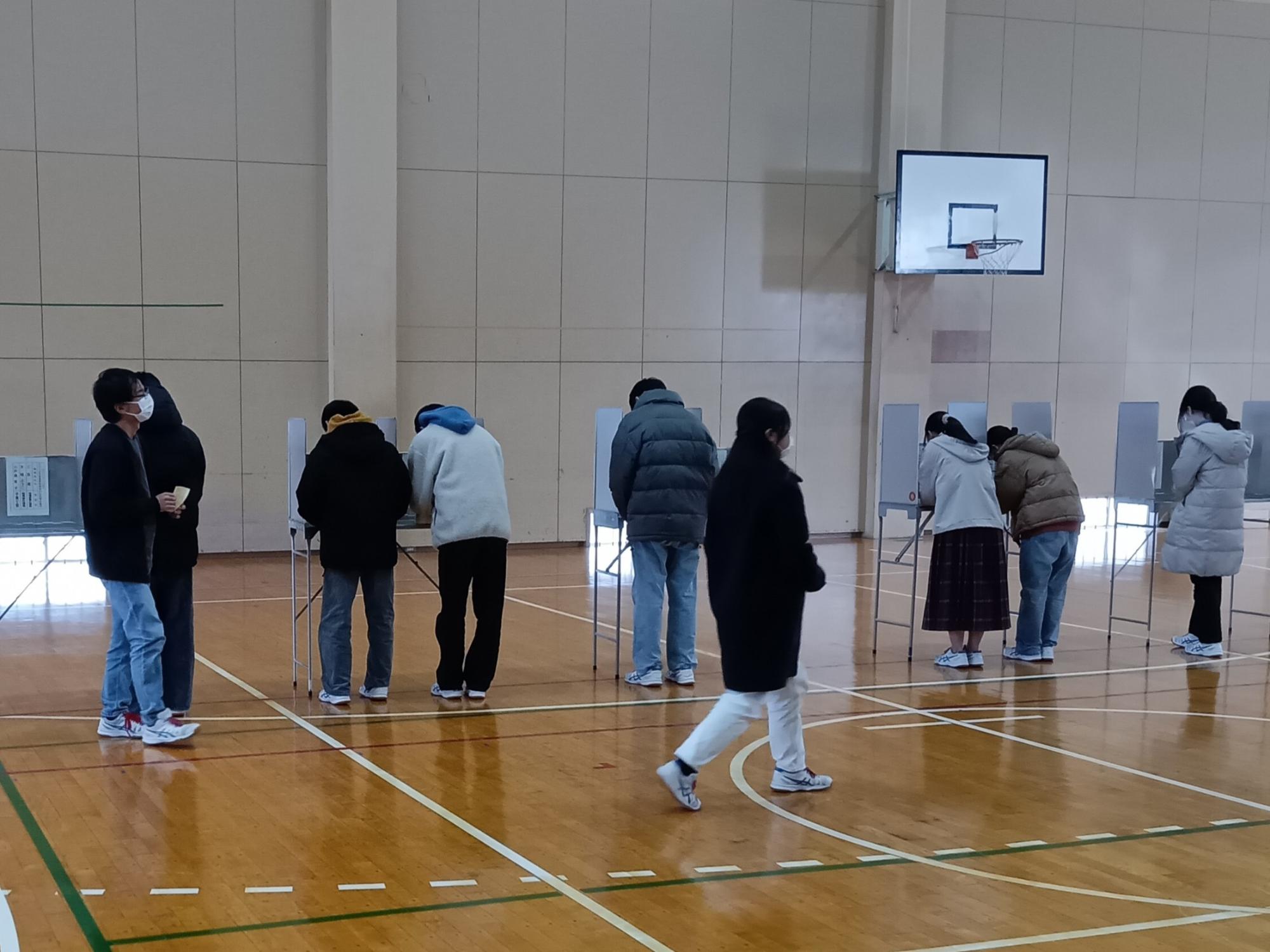 写真：体育館に投票用記載台を置き、子どもたちが模擬選挙をしている様子
