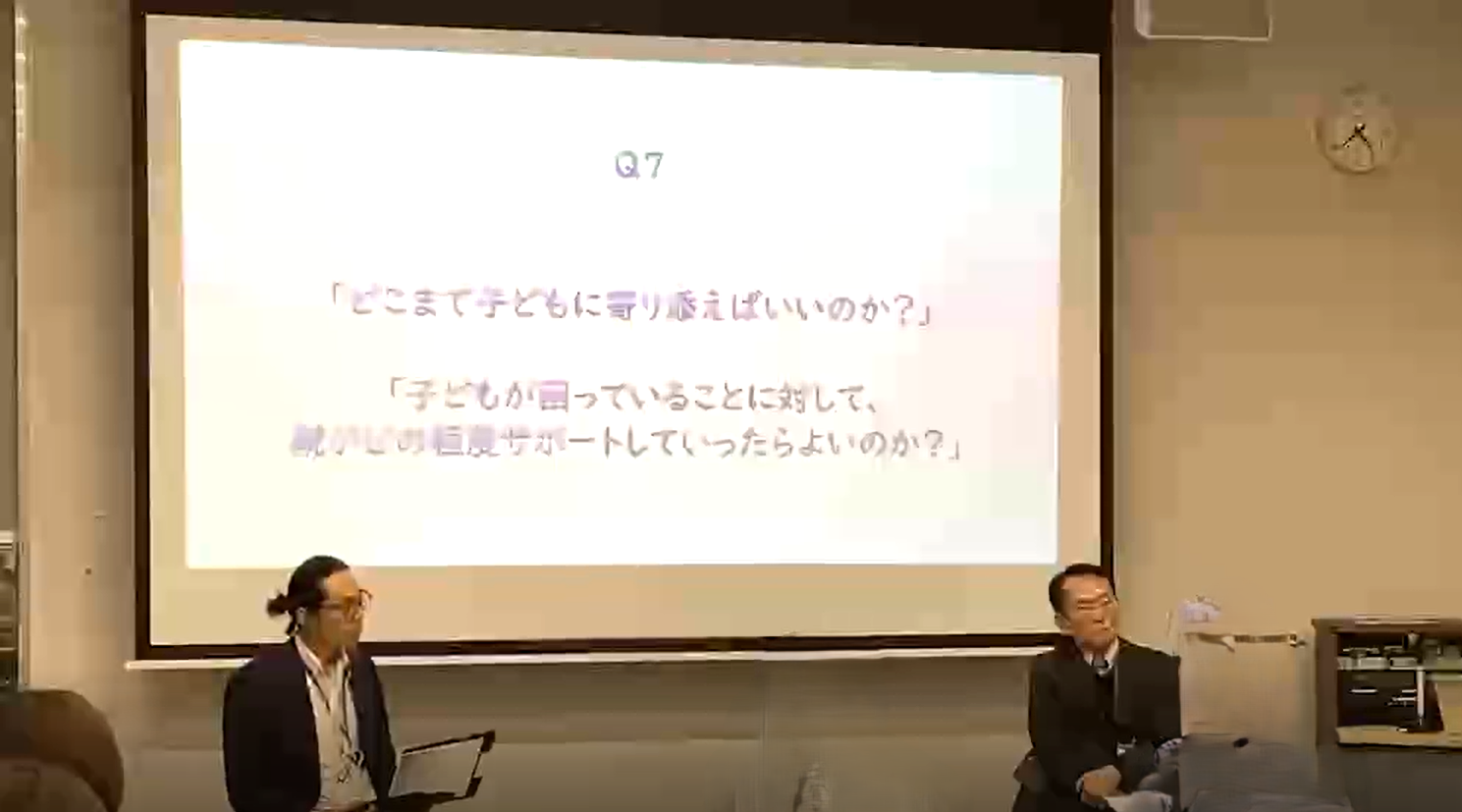 写真：意見交換の様子。質問がスライドに移され、2人の男性講師が答えている様子