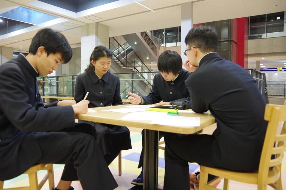 写真：17歳当時の小倉さんと同級生。フォンジェに設置されたテーブルで、頭を寄せ合い課題に向き合っています