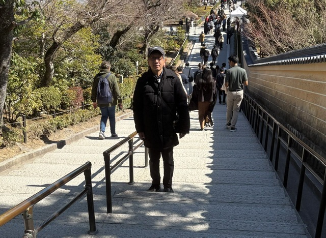 写真：高校の修学旅行で撮影した場所と同じポイント写真に納まる田平さん