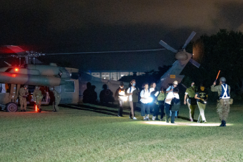 写真：広場に着陸している自衛隊ヘリコプターのそばを、自衛隊員の誘導で歩いている訓練参加市民の皆さん