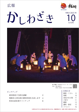 広報かしわざき2022年10月号の表紙：狐のお面をつけた白装束姿の人らが丸く集まり、行灯の光に照らされながら踊る様子