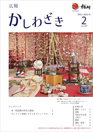 広報かしわざき2023年2月号の表紙：赤の毛せんや着物の帯と一緒に、つるし雛や親王雛、雪割草が飾られています。