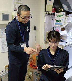 写真：タブレットを見ている会田さんと、タブレット画面を指さす若月さん