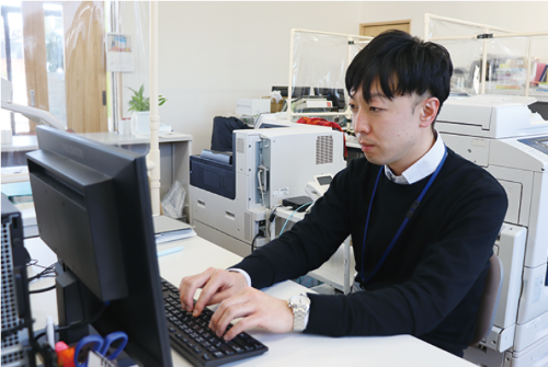 写真：事務所でパソコンに向かい、ケアプランを作成する山田さん