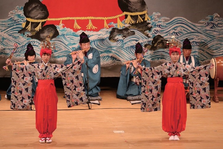 写真：高原田の小切子踊。赤いユライの上にきらびやかな冠をかぶり、赤い袴の裾を縛った衣装で、綾竹を打ち鳴らして踊ります。