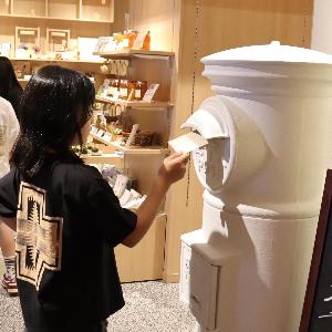 写真：西山ショップ内にある白色の未来ポスト。女の子が手紙を投函しています。