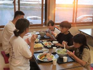 写真：夕日が差し込む食堂で、食事を楽しむ5人の家族