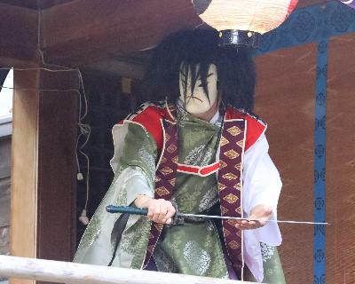 写真：右手に剣を持ち、寝かせた刃に左手を添えた、神楽舞の一場面。