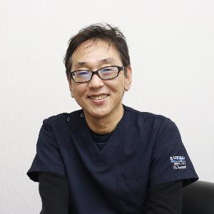 写真：眼鏡をかけた津吉医師がにこやかに微笑んでいます