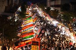 写真：夜のえんま市。出店の明かりが通りの奥まで続き、たくさんの人出でごった返しています