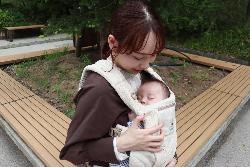 写真：抱っこひもの中ですやすや眠るお子さんを見つめる金子さん
