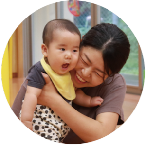 写真：立っちしている赤ちゃんを抱きしめるお母さん