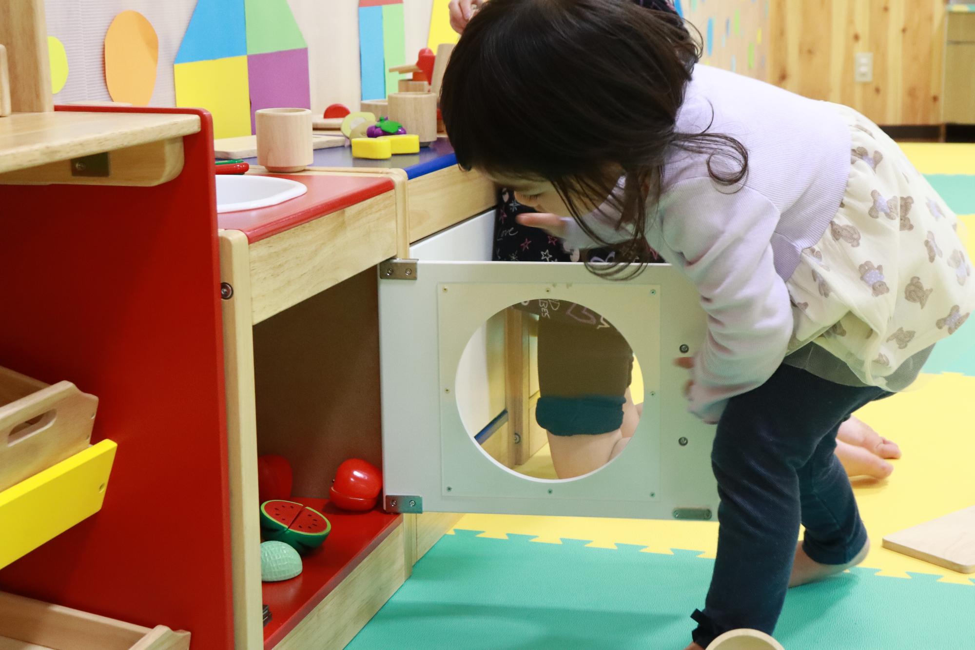 写真：静かな遊びエリアにある木製台所でおままごとをして遊ぶ女の子