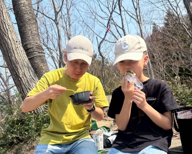 写真：おにぎりやお弁当をほおばる子どもとお父さん