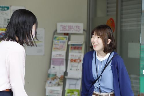 写真：店舗入り口で来店客と談笑する尾崎さん