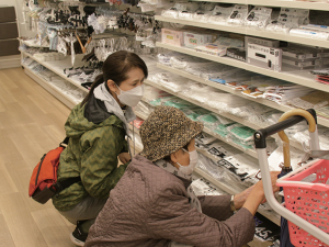写真：買い物に付き添った店内で、しゃがんで商品を選ぶ利用者と坂井さん